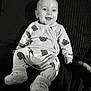 baby, smiling, infant, pajamas, bear_pattern, booties, sitting, face, cute, child, cozy, happy, indoors, portrait, black_and_white, soft_texture, clothing, person, comfortable, joyful