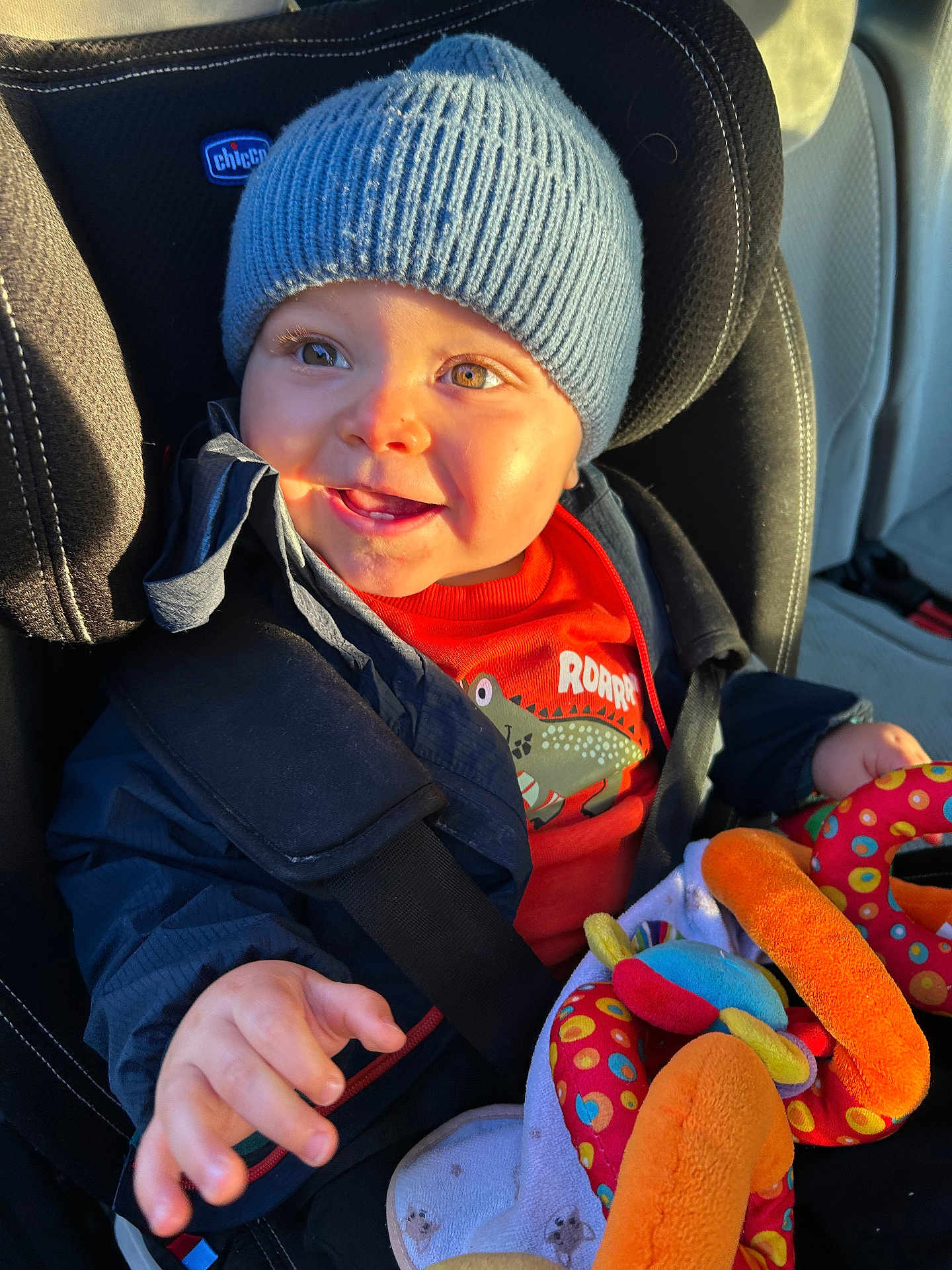 Alessio a rejoint le concours — aidez-le/la à gagner de superbes lots ! toddler, child, car_seat, blue_hat, jacket, plush_toy, colorful_toy, happy, smiling, indoors, seatbelt, clothing, person, face, hand, sunlight, car_interior, window_light, cute, baby