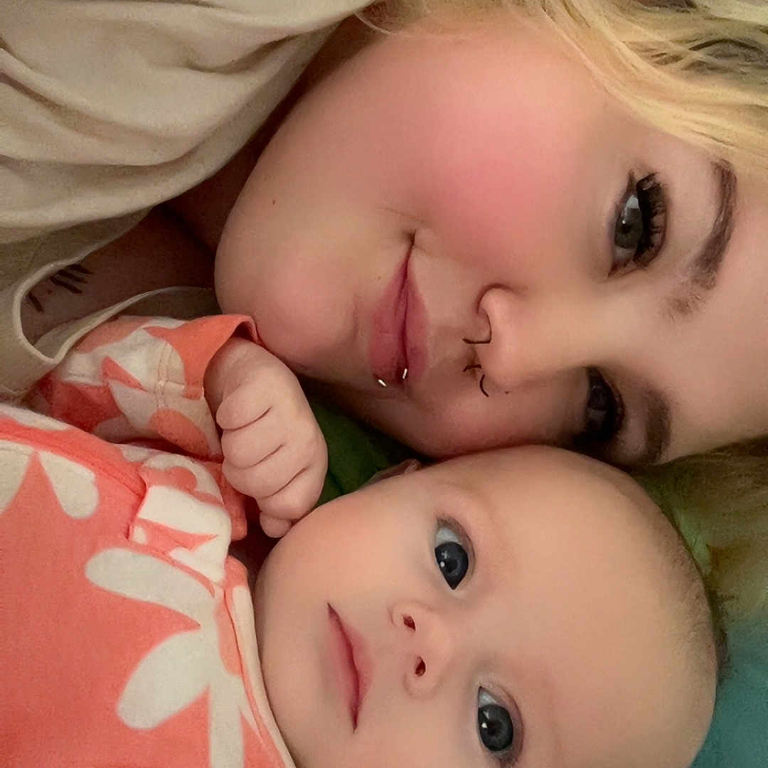 Lillianna is registered to the contest to win money with this photo: baby, bed, bedding, blanket, closeup, comfort, eyelashes, face, family, flower_pattern, head, infant, lying_down, person, piercing, pink, portrait, skin, sleepwear, togetherness