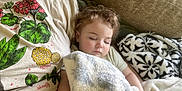 Adelaide joined the competition — help win amazing prizes! toddler, sleeping, blanket, couch, child, person, adult, shirt, floral_print, curly_hair, rest, cozy, indoors, nap, soft_texture, comfort, relaxation, home, casual_clothing, peaceful