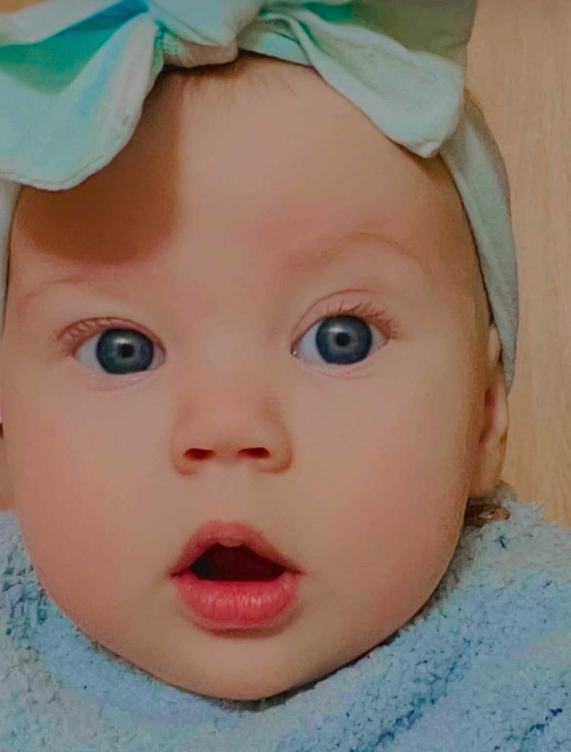Paige is registered to the contest to win money with this photo: baby, face, closeup, blue_eyes, headwrap, clothing, expression, surprised, cute, infant, child, skin, portrait, young, human, apparel, headwear, indoors, soft_texture, adorable