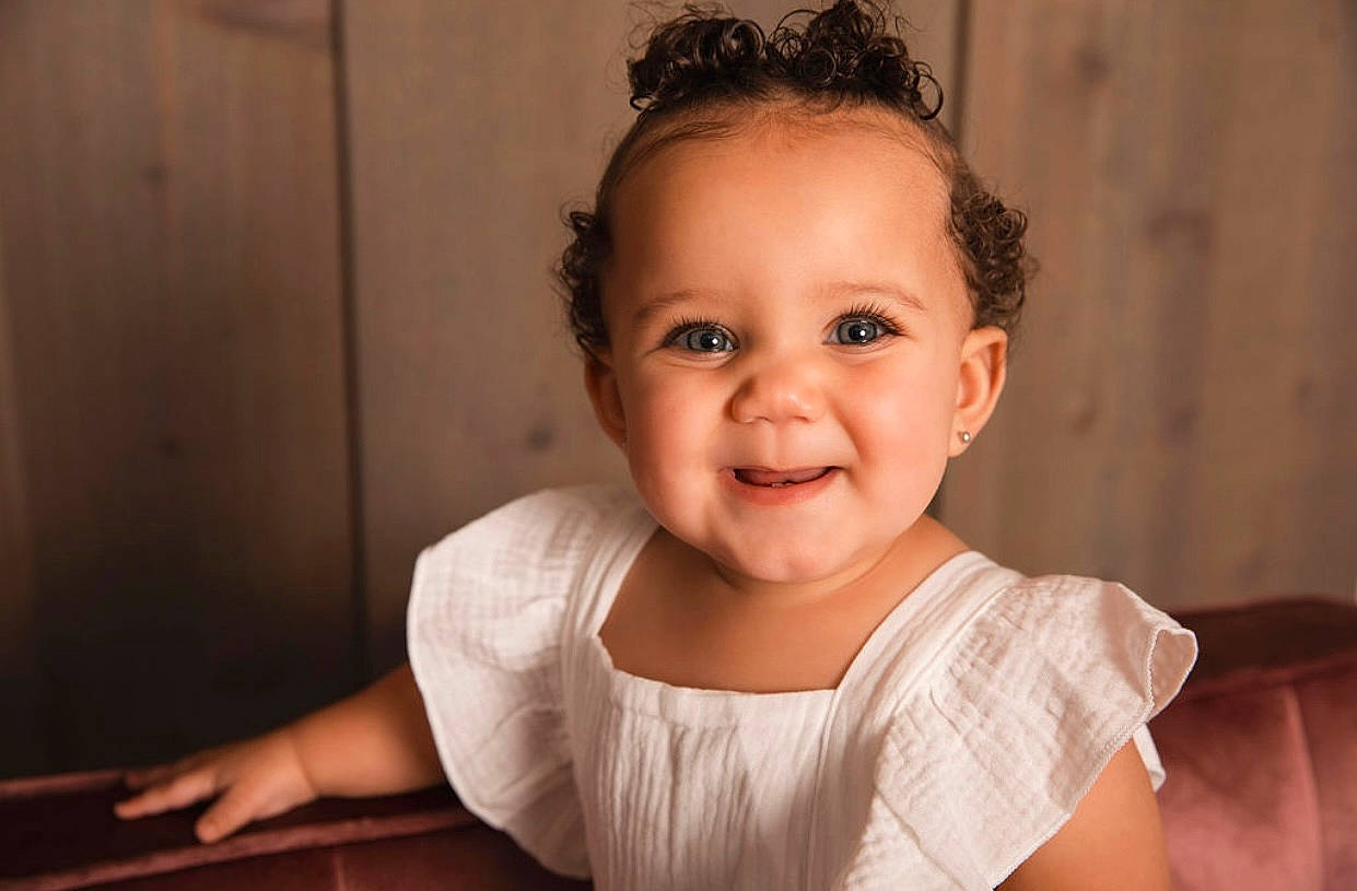 Kapri is registered to the contest to win money with this photo: baby, baby_toddler_clothing, cheek, child, dress, embellishment, eyebrow, eyelash, flash_photography, fun, happy, headpiece, iris, joy, person, portrait, portrait_photography, sitting, sleeve, smile