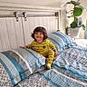 Aziel is registered to the contest to win money with this photo: toddler, child, bed, pajamas, yellow_stripes, smile, indoor, plant, pillow, bedspread, headboard, wall_art, hair, happy, furniture, home, room, curtains, sunlight, cozy