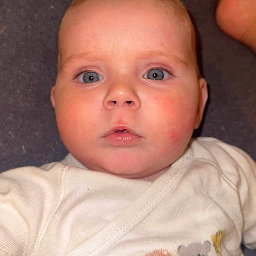 Fahed participe au concours pour gagner de l'argent avec cette photo : animal_print, baby, baby_garment, blue_eyes, child, clothing, cute, expression, face, head, indoors, infant, lying_down, onesie, person, portrait, skin, soft_lighting, white_clothing, young_child