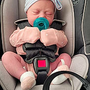 Ayda is registered to the contest to win money with this photo: newborn, baby, car_seat, pacifier, pink_clothing, striped_hat, bow, sleeping, infant, safety_harness, closeup, child, cute, indoors, soft_lighting, sock, seatbelt, resting, adorable, transportation
