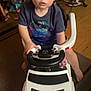 child, toddler, toy_car, indoor, steering_wheel, footwear, clothing, floor, car_toy, person, young_child, head, eyes, expression, sitting, wood_floor, furniture, chair, casual, play