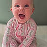 Bexley is registered to the contest to win money with this photo: baby, infant, smiling, happy, pajamas, pink, floral, sitting, child, cute, portrait, face, hands, feet, indoors, expression, joy, young, person, cozy