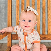 Bexley joined the competition — help win amazing prizes! baby, child, infant, sitting, wooden_chair, headband, tongue_out, cute, playful, indoor, person, smiling, blue_eyes, short_hair, onesie, hand, foot, expression, wood, furniture