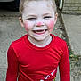 Kailynn is registered to the contest to win money with this photo: child, smiling, red_shirt, grinch, holiday_clothing, long_sleeves, patterned_pants, outdoor, concrete, brick_wall, vintage_car, high_ponytail, rosy_cheeks, missing_teeth, happy, person, cute, playful, casual, daylight