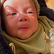 Jeremiah joined the competition — help win amazing prizes! baby, child, face, hat, knit_hat, jacket, green_bib, mitten, dinosaur_pattern, sunlight, shadow, close_up, infant, cute, warm_clothing, indoor, soft_light, expression, person, bundle