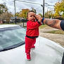 Tayzon is registered to the contest to win money with this photo: toddler, child, red_outfit, sneakers, car_hood, adult_arm, tattoo, suburban, autumn, trees, cloudy_sky, sidewalk, fence, grass, street, residential, outdoor, balance, holding_hand, portrait