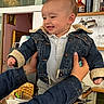 Ange a rejoint le concours — aidez-le/la à gagner de superbes lots ! baby, denim_jacket, smiling, child, indoor, kitchen, wooden_table, adult_hands, bottle, jar, shelf, cupboard, white_socks, casual_clothing, happy, portrait, person, holding, table, cozy