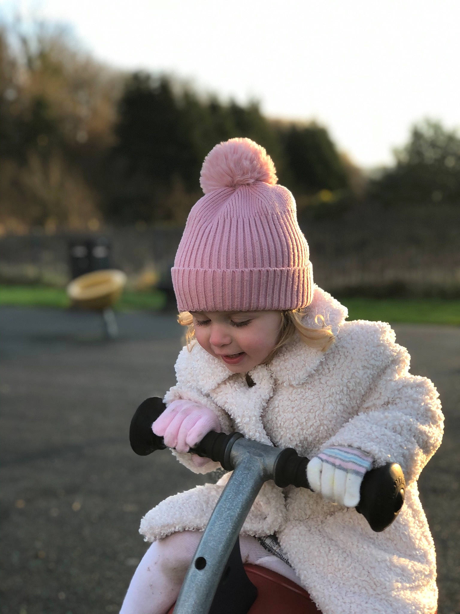 Olivia-rose is registered to the contest to win money with this photo: baby, baby_toddler_clothing, cap, child, freezing, fun, fur, glove, grass, happy, headwear, jacket, knit_cap, mammal, person, sitting, sky, toddler, tree, winter