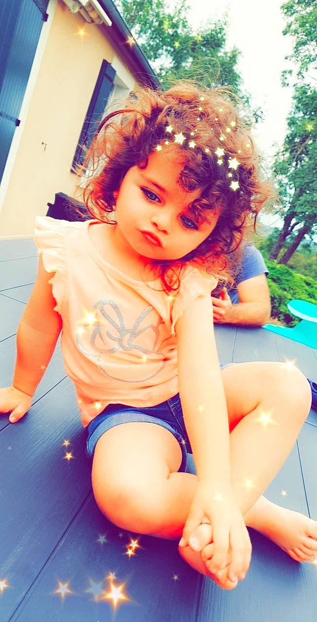 Clara participe au concours pour gagner de l'argent avec cette photo : baby_toddler_clothing, blue, facial_expression, fun, grass, hair, hairstyle, happy, head, human_body, knee, leg, leisure, long_hair, person, pink, shorts, skin, sunlight, thigh