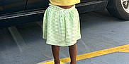 Madison is registered to the contest to win money with this photo: arms_raised, braided_hair, car, casual_clothing, child, concrete, daylight, footwear, green_skirt, happy, outdoor, parking_lot, person, reflection, smiling, sparkly_shoes, standing, toddler, vehicle, yellow_tshirt