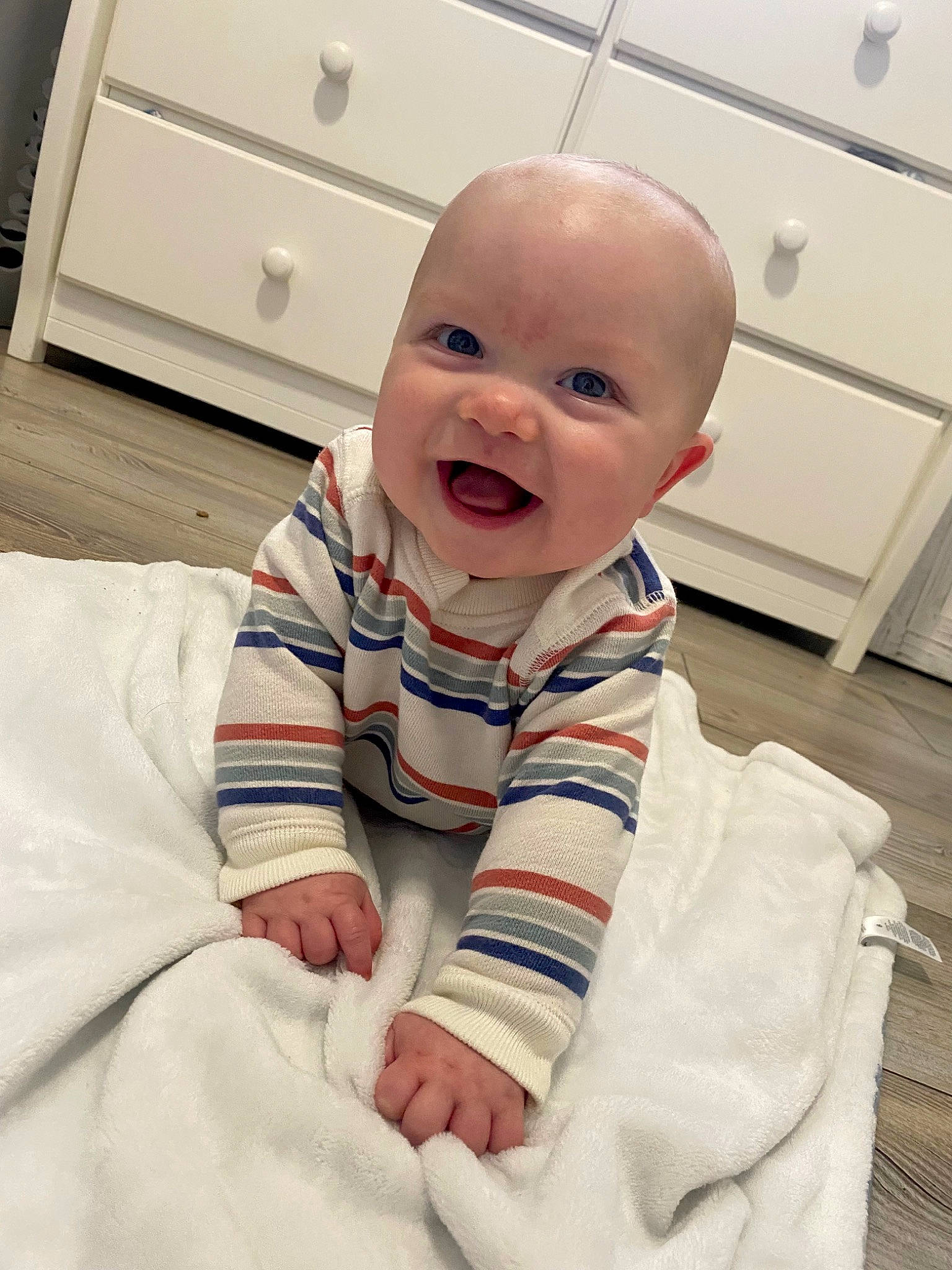 Hudson is registered to the contest to win money with this photo: baby, baby_toddler_clothing, cabinetry, cheek, collar, comfort, eye, face, floor, flooring, happy, head, iris, mouth, person, skin, sleeve, smile, standing, toddler