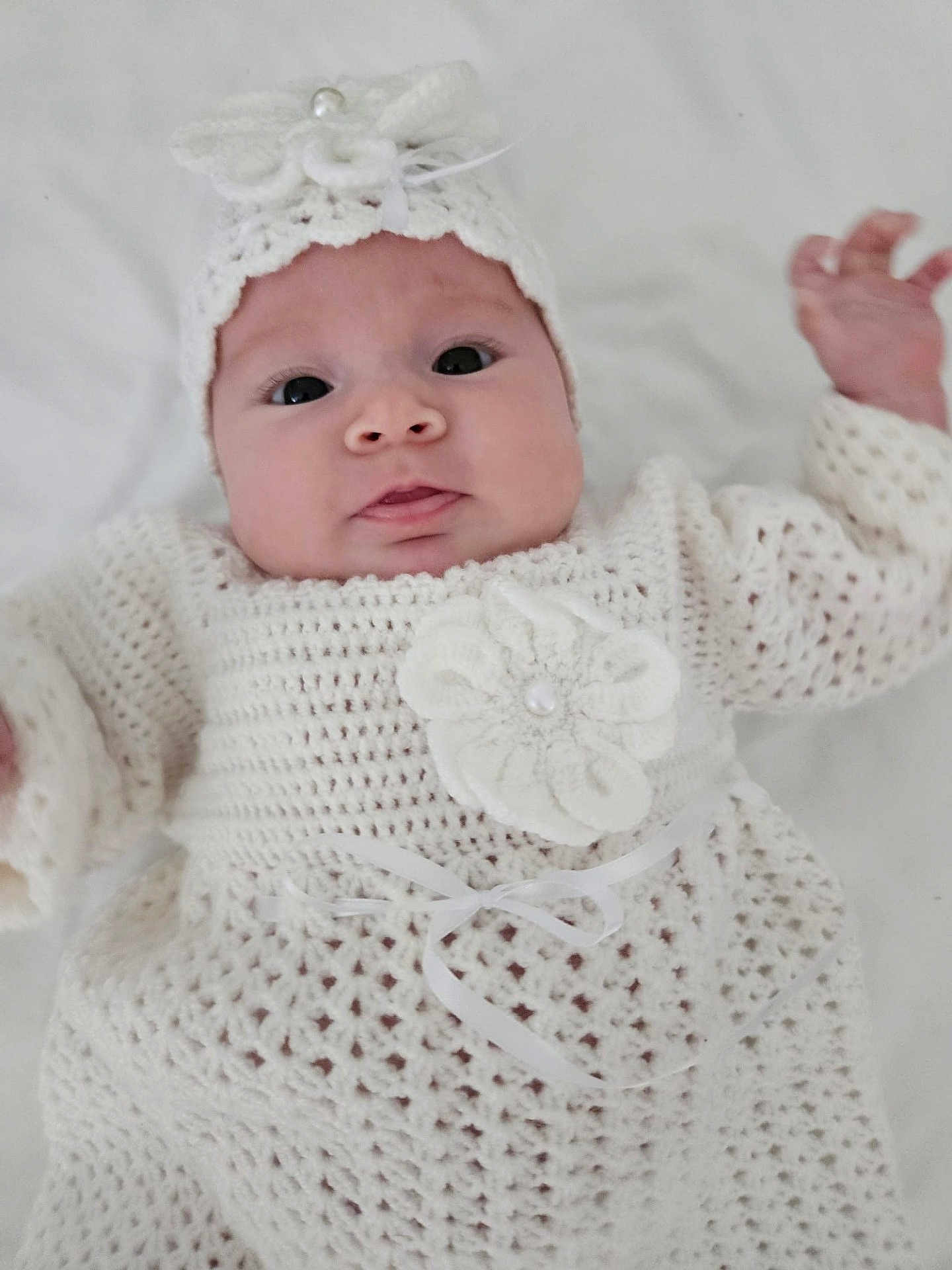 Ashley joined the competition — help win amazing prizes! baby, infant, crochet, white_clothing, headband, hand, face, cute, portrait, newborn, child, soft_texture, fabric, ribbon, closeup, small_hand, lying_down, indoors, adorable, person