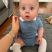 Rome joined the competition — help win amazing prizes! baby, child, blue_outfit, knitted_clothing, white_socks, knee_high_socks, sitting, wide_eyes, surprised_expression, hand, adult_hand, rug, gray_rug, indoor, wooden_floor, couch, stuffed_toy, giraffe_toy, person, portrait