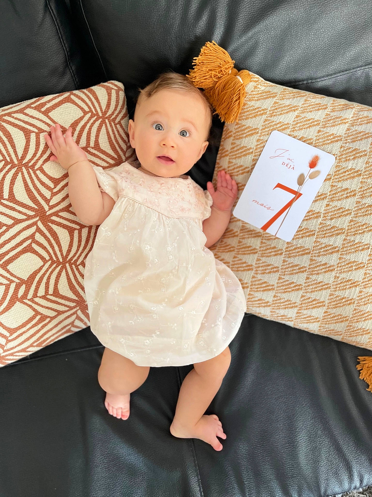 Lyana participe au concours pour gagner de l'argent avec cette photo : baby, baby_toddler_clothing, child, comfort, couch, day_dress, dress, finger, flash_photography, foot, gesture, happy, human_leg, linens, one_piece_garment, pattern, person, sitting, skin, sleeve