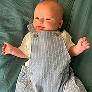 Dayton joined the competition — help win amazing prizes! baby, infant, smiling, tongue_out, blue_overalls, striped_clothing, white_shirt, lying_down, blanket, teal_background, cute, happy, child, skin, head, hand, button, fabric, portrait, playful