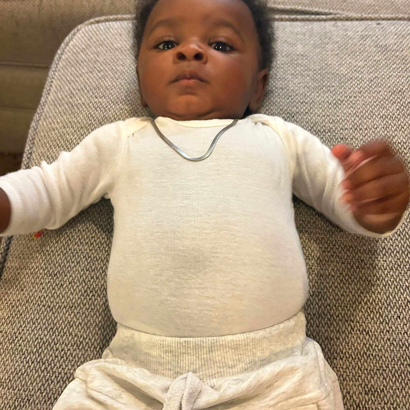 Kamino joined the competition — help win amazing prizes! baby, infant, child, couch, clothing, white_shirt, pants, necklace, lying_down, indoor, portrait, face, person, furniture, expression, young_child, home, casual, cute, relaxed