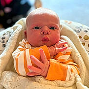 Ava joined the competition — help win amazing prizes! baby, infant, face, hands, blanket, clothing, orange_stripes, expression, cute, newborn, wrapped, cozy, portrait, indoor, soft_light, skin, person, closeup, warm, child