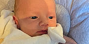 Samantha is registered to the contest to win money with this photo: baby, infant, blanket, purple_sweater, cushion, striped_fabric, face, eyes, clothing, newborn, soft_texture, indoor, resting, closeup, child, portrait, warm, cute, person, young