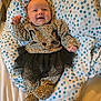 Samantha is registered to the contest to win money with this photo: baby, infant, smiling, leopard_print, onesie, tutu, black_tutu, blanket, polka_dot, blue, white, happy, child, lying_down, cute, fist_raised, face, person, clothing, bed