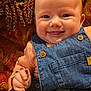 baby, book, button, child, clothing, couch, cozy, cushion, denim_overalls, face, hand, happy, indoor, infant, peach_shirt, person, portrait, skin, smiling, textile