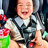 Hamlin is registered to the contest to win money with this photo: baby, child, infant, laughing, smiling, portrait, car_seat, safety_harness, buckled, vehicle, indoors, close_up, face, eyes_closed, happy, sitting, bottle, colorful, casual_clothing, daylight