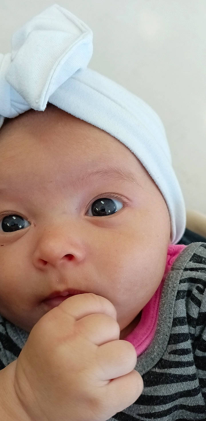 A'Myia is registered to the contest to win money with this photo: baby, cap, cheek, chin, eye, eyebrow, eyelash, face, gesture, head, headgear, headwear, iris, lip, mouth, nose, organ, person, pink, skin