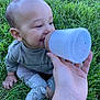 baby, child, grass, outdoor, hand, bottle, sitting, clothing, footwear, slippers, happy, person, infant, nature, greenery, cute, feeding, toddler, skin, smile