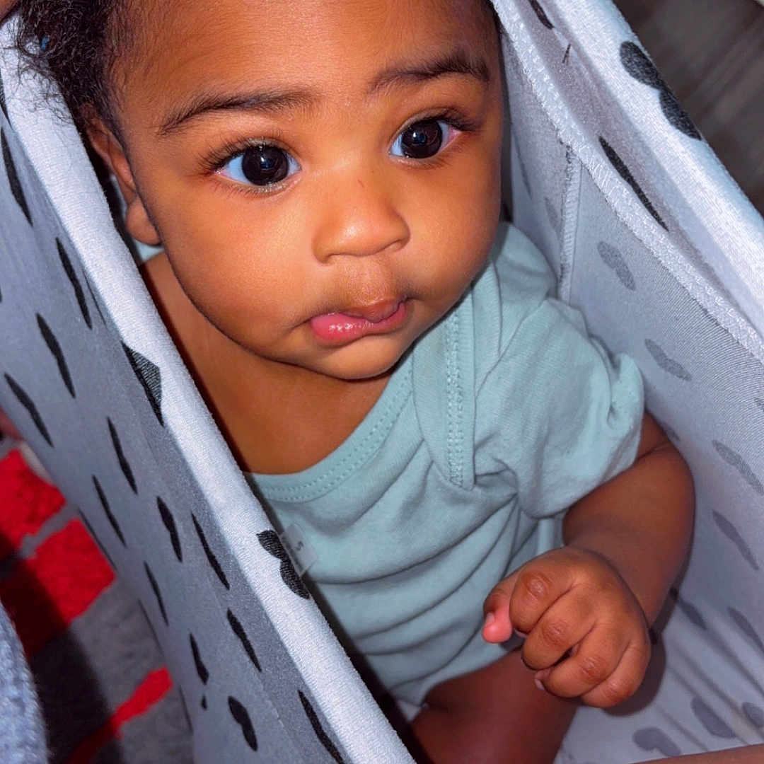 Juelz joined the competition — help win amazing prizes! baby, child, curious, indoors, laundry_basket, patterned, peeking, cute, infant, clothing, skin, hand, portrait, expression, looking_up, closeup, person, young, playful, home
