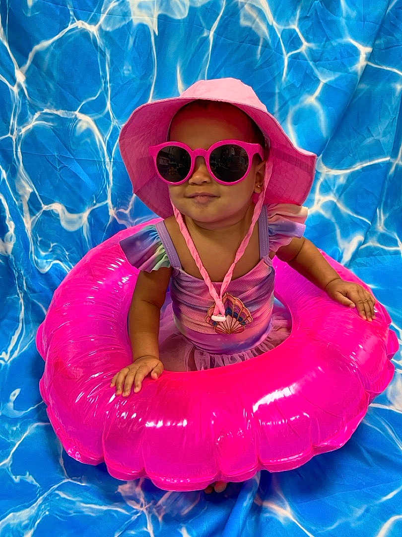 Miabelle is registered to the contest to win money with this photo: toddler, child, pink_hat, sunglasses, inflatable_ring, swimwear, summer, blue_background, water_pattern, portrait, cute, fashion, accessories, playful, indoor, colorful, smiling, baby, fun, vacation