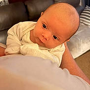 Catalina is registered to the contest to win money with this photo: baby, infant, person, face, eyes, clothing, arm, hand, indoor, couch, blanket, skin, head, newborn, holding, portrait, expression, curious, warm_light, cozy