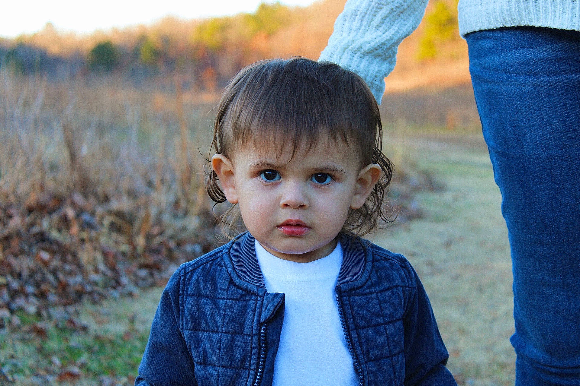 Liam is registered to the contest to win money with this photo: blue, child, clothing, electric_blue, eye, fun, gesture, grass, grass_family, grassland, happy, head, iris, outerwear, people_in_nature, person, plant, standing, sunlight, toddler