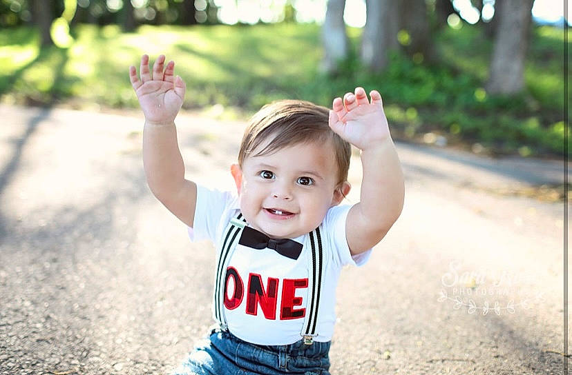 Liam is registered to the contest to win money with this photo: baby, baby_toddler_clothing, face, facial_expression, finger, flash_photography, gesture, grass, hand, happy, joy, leaf, leisure, people_in_nature, person, plant, skin, sleeve, smile, standing