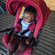 Liam joined the competition — help win amazing prizes! baby, bicycle, black_hair, brown_pants, car_seat, casual_clothing, child, garage, indoor, person, red, resting, safety, seat, socks, straps, thoughtful, tiled_floor, toddler, white_shirt