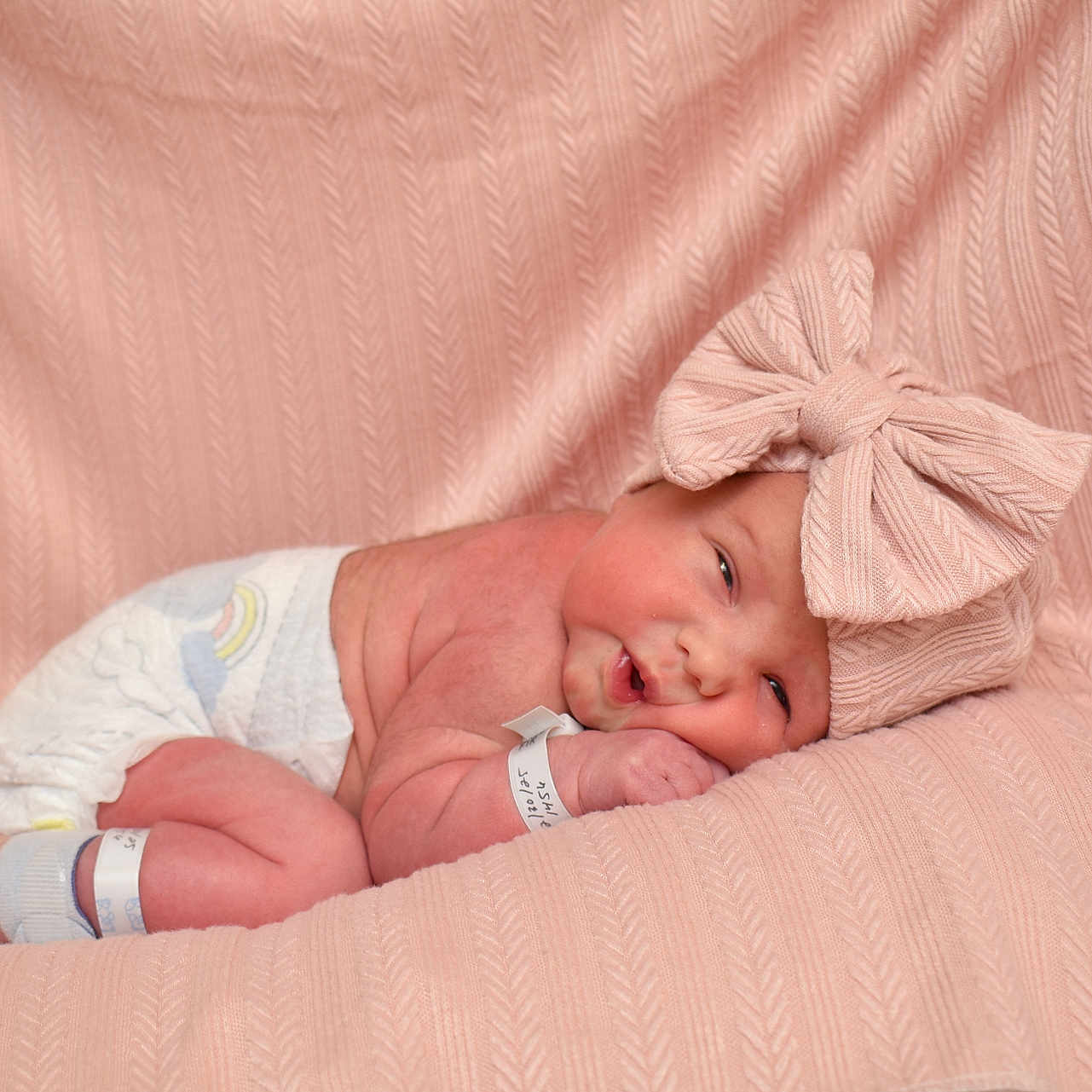 Oliviana is registered to the contest to win money with this photo: baby, blanket, bow_headband, cozy, cute, diaper, eyes_open, fabric_texture, hospital_band, infant, large_bow, newborn, newborn_pose, pink_blanket, portrait, skin, sleeping, soft_lighting, studio_photo, wristband