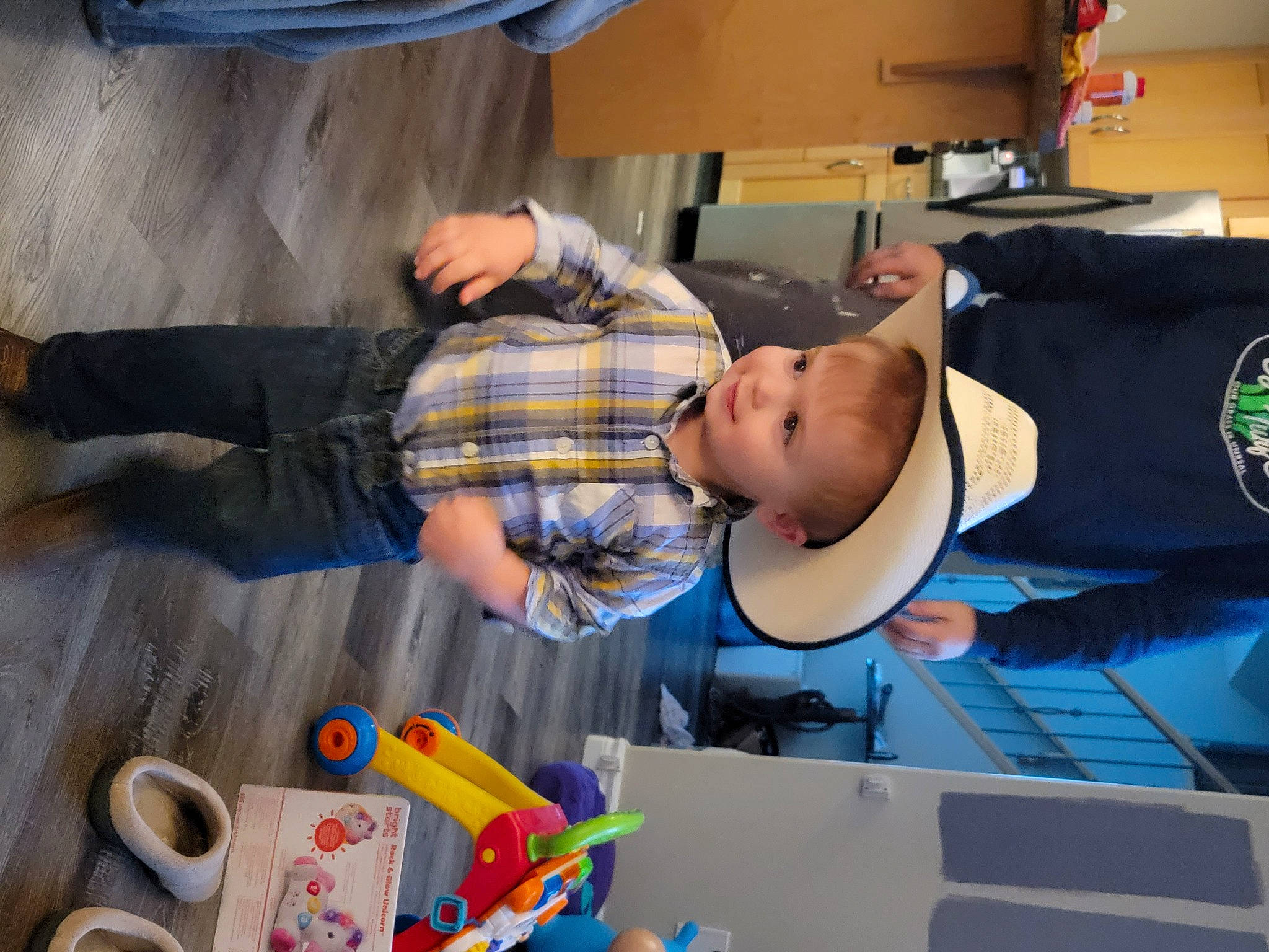 Declan is registered to the contest to win money with this photo: baby, baby_toddler_clothing, child, coffee_cup, comfort, cup, curtain, flooring, fun, hat, mug, office_supplies, person, play, room, serveware, t_shirt, tableware, toddler, toy