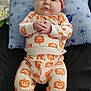 Michael is registered to the contest to win money with this photo: baby, blanket, blue_pillow, child, clothing, cozy, cute, hand_clasped, happy, indoors, infant, lying_down, orange_booties, orange_hat, pillow, portrait, pumpkin_outfit, smiling_face, soft_toys, stars_pattern