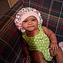 Ro'Miyah is registered to the contest to win money with this photo: baby, infant, toddler, bonnet, hat, polka_dot, green_onesie, smile, dimple, eyes, hand, leg, couch, plaid, fabric, living_room, cozy, portrait, person, furniture