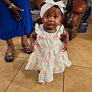 Zunaisha is registered to the contest to win money with this photo: adult, baby, blue_dress, child, curious, expression, floor, footwear, furniture, hand, headband, home, indoor, leather_chair, person, portrait, support, tile, walking, white_dress