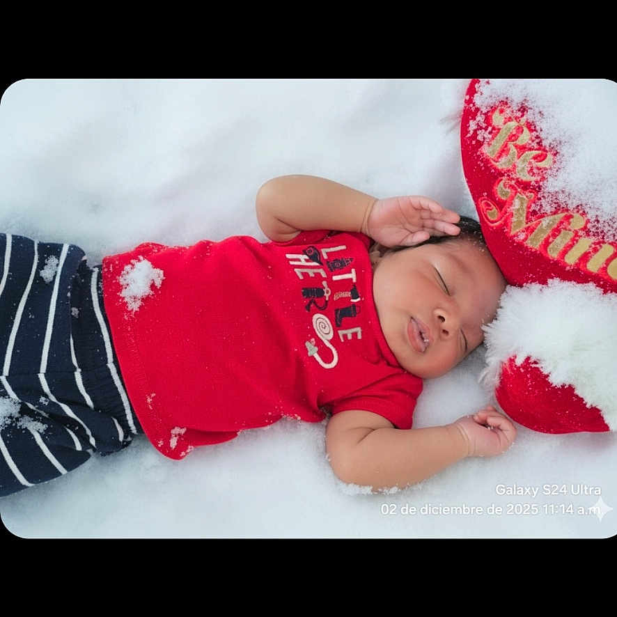 Darvin is registered to the contest to win money with this photo: baby, child, clothing, cute, face, festive, hand, holiday, infant, outdoor, peaceful, pillow, red_shirt, resting, skin, sleeping, snow, striped_pants, textile, winter
