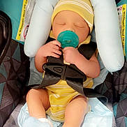 Zamari joined the competition — help win amazing prizes! baby, infant, car_seat, pacifier, yellow_clothing, hat, sleeping, socks, safety_straps, cushion, warning_label, child, indoors, newborn, resting, person, cute, comfort, head_support, seat