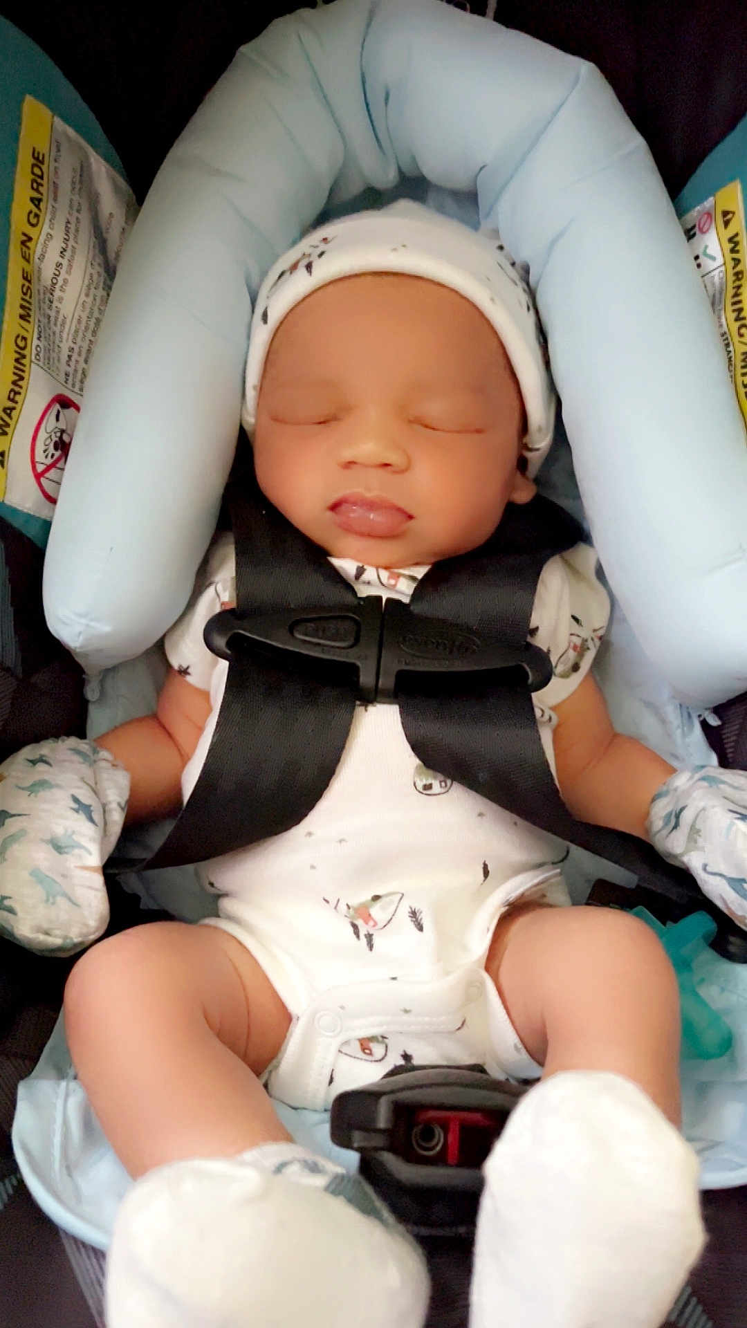 Zamari is registered to the contest to win money with this photo: baby, sleeping, car_seat, mittens, hat, infant, child, safety_straps, blue_cushion, white_clothing, newborn, peaceful, cute, soft, indoor, portrait, small_hands, small_feet, comfort, resting