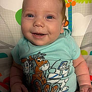 Anthelion is registered to the contest to win money with this photo: baby, baby_seat, blue_clothing, cartoon_characters, child, colorful, cute, face, hand, happy, indoor, infant, onesie, patterned_background, playful, portrait, sitting, skin, smiling, toy_story