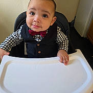 Maze is registered to the contest to win money with this photo: baby, bow_tie, checkered_shirt, child, clothing, cute, expression, eyes, face, furniture, hands, high_chair, indoor, person, portrait, skin, smile, table, vest, young_child