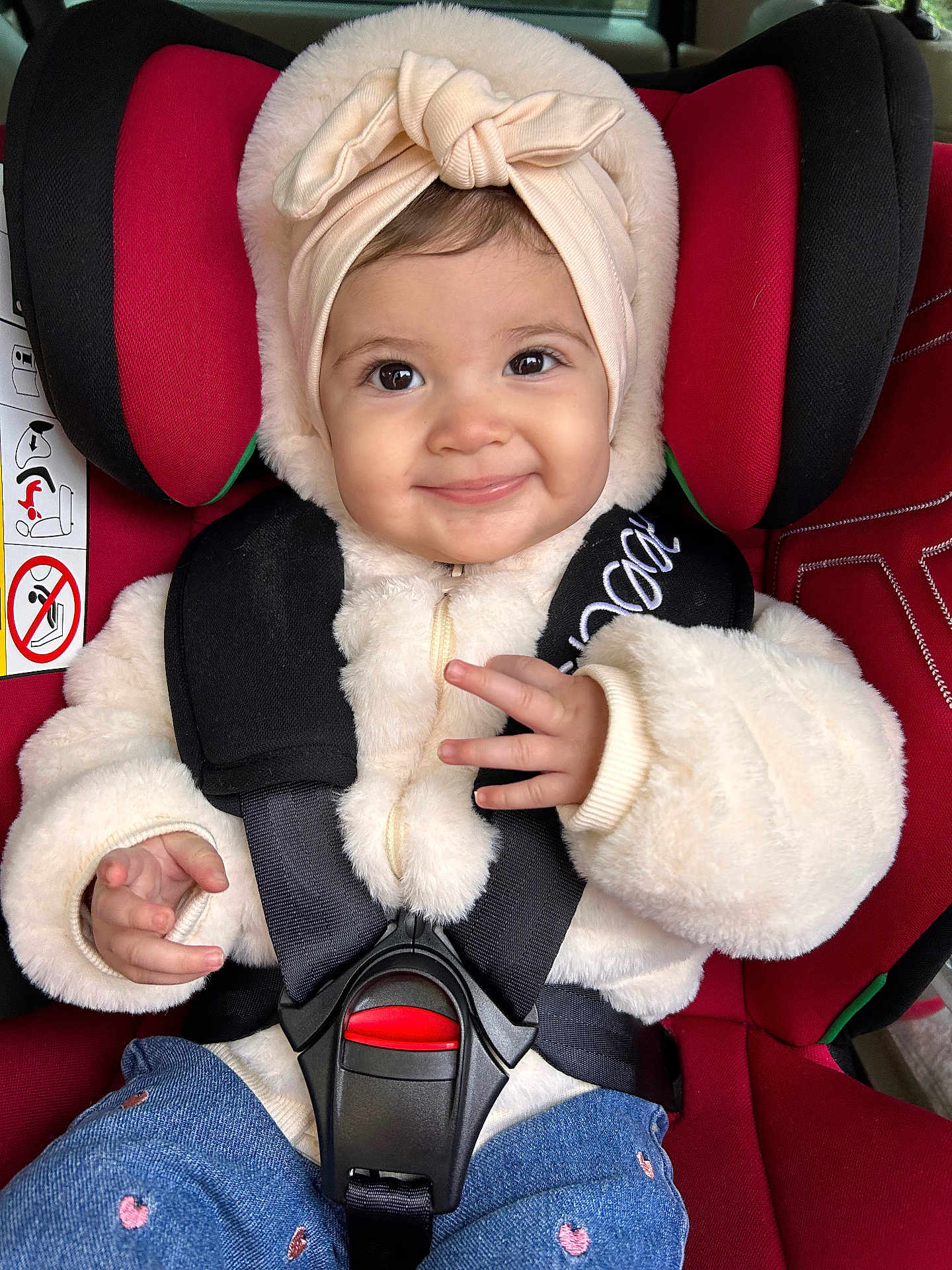 Siana participe au concours pour gagner de l'argent avec cette photo : baby, car_seat, child, smile, headband, jacket, fur, red, black, blue, jeans, cute, happy, infant, seatbelt, clothing, portrait, indoors, person, hand