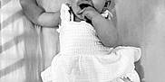 Abigaëlle participe au concours pour gagner de l'argent avec cette photo : baby, child, infant, dress, headband, bow, smile, happy, hand, fingers, lying_down, soft_surface, monochrome, black_and_white, cute, young, portrait, cheerful, shadow, clothing